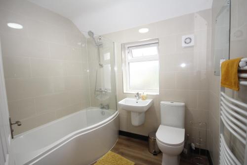 a bathroom with a tub and a toilet and a sink at The Heathrow House in Cranford