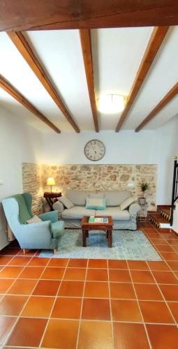 a living room with couches and a clock on the wall at MASÍA de SAN JUAN CASA NÚMERO 1 en Castillo con piscina y Aire Acondicionado in Segorbe