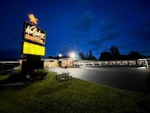 un cartello per un motel di Hollywood di notte di Holiday Motel a Sault Ste. Marie