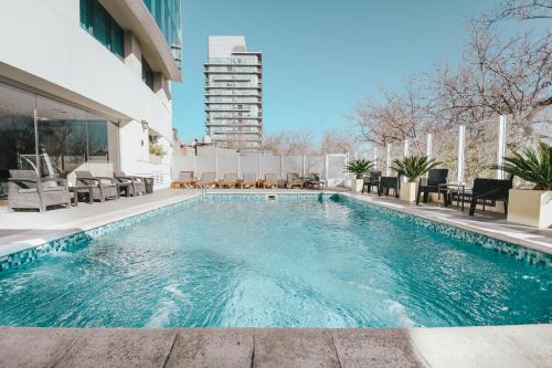 a swimming pool with chairs and a building in the background at DiplomaticHotel in Mendoza