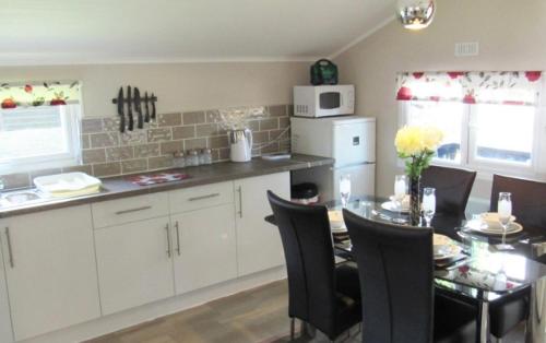 a kitchen with a table with chairs and a counter top at Peregrine Lodge - idillic Cornwall retreat in Liskeard
