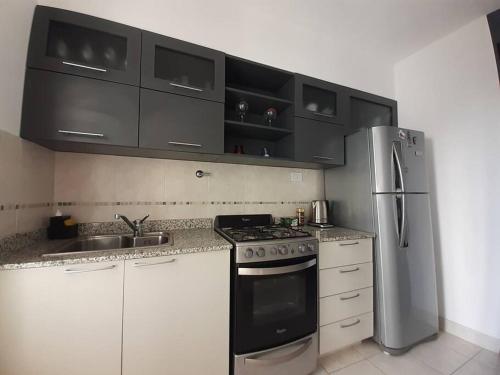 a kitchen with white cabinets and a stainless steel refrigerator at Hermoso Dpto completo en el corazón de Santa Fe in Santa Fe