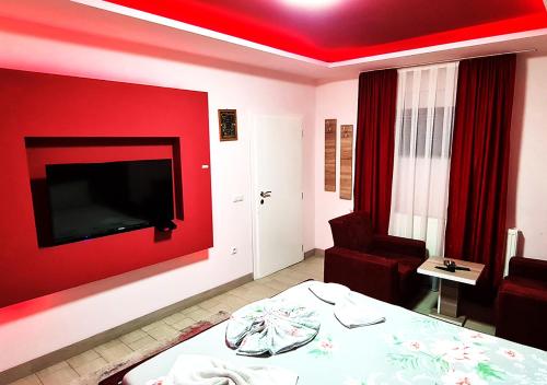 a room with a red wall with a bed and a chair at Motel Villa STAR in Gjilan