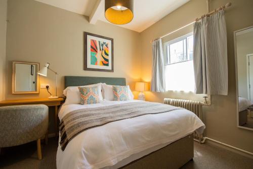 a bedroom with a bed and a desk and a window at The Rose & Crown, Ashbury in Ashbury