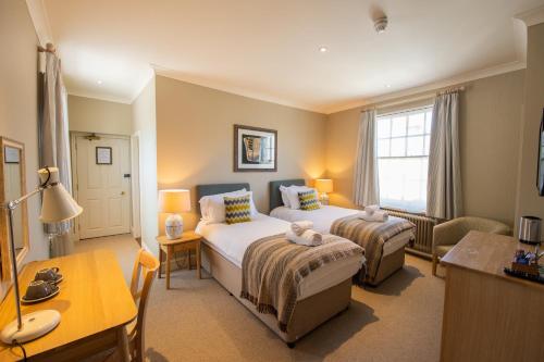 a bedroom with two beds and a table and a desk at The Rose & Crown, Ashbury in Ashbury