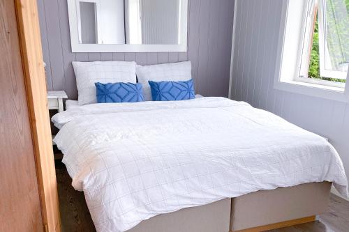 Fedafjorden Apartments في Feda: غرفة نوم بسرير ابيض مع مخدات زرقاء