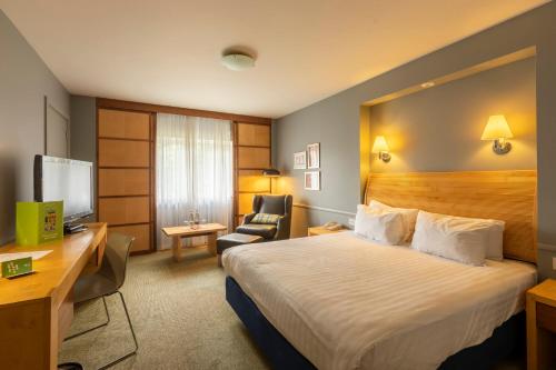 a hotel room with a bed and a desk and a chair at Holiday Inn Guildford by IHG in Guildford