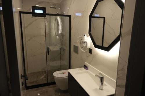 a bathroom with a shower and a toilet and a sink at The Pearl Airport Hotel in Arnavutköy