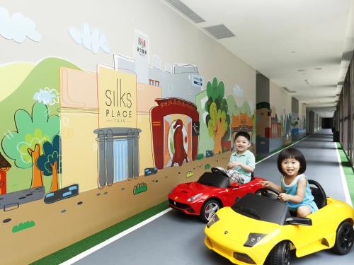 two children riding on toy cars in a hallway at Silks Place Yilan in Yilan City