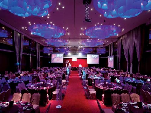a room full of tables and chairs with a person on the stage at Silks Place Yilan in Yilan City