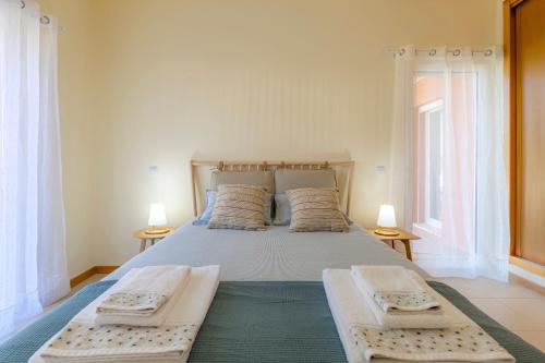 a bedroom with a large bed with two windows at Casa Kiko in Burgau