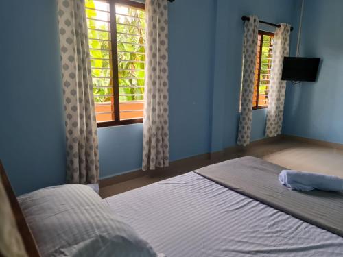 a bedroom with a bed and two windows at Nalluran illam - 2 bed room in Jaffna