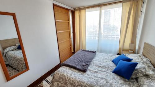 - une chambre avec un miroir et un lit avec des oreillers bleus dans l'établissement San Diego, à Santiago