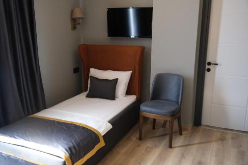 a small bedroom with a bed and a chair at The Pearl Airport Hotel in Arnavutköy