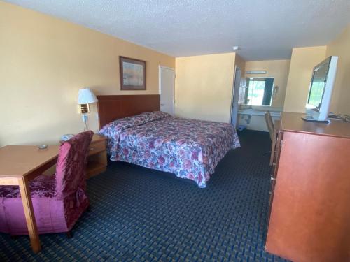 a hotel room with a bed and a chair at Budget inn in Alma