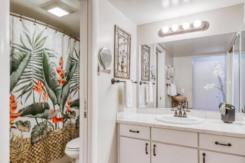 a bathroom with a toilet and a sink with a tropical shower curtain at Greens At Waikoloa L101 in Waikoloa Village