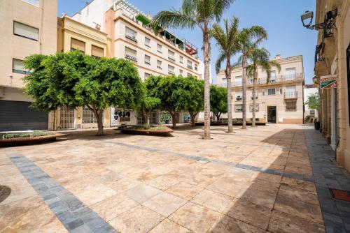 un patio vacío con palmeras y edificios en Be Free Arco Almeria, en Almería