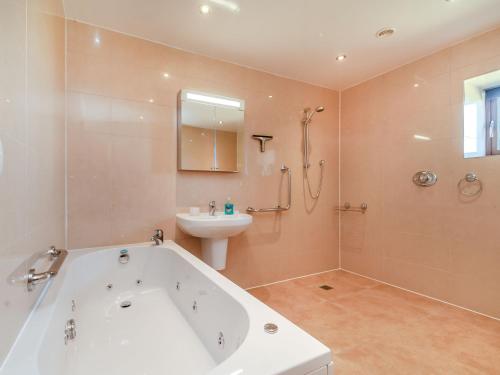 a bathroom with a bath tub and a sink at Routster Cottage in Giggleswick