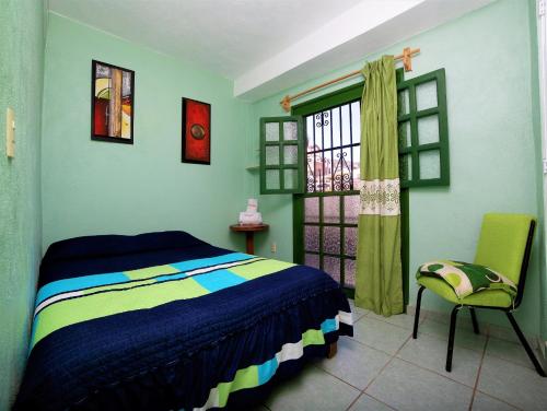 um quarto com uma cama, uma janela e uma cadeira em María Bonita by Rotamundos em Taxco de Alarcón