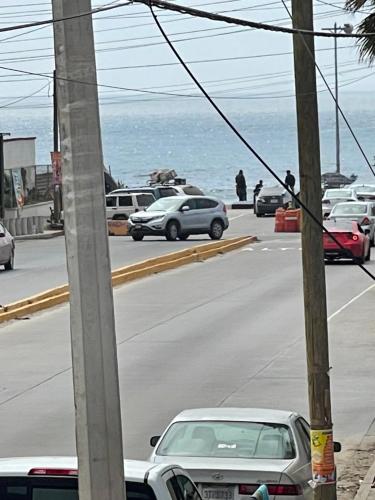 a street with cars driving down a road near the ocean at Seaside Adventure Lodging in Ensenada