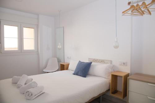Un dormitorio con una cama blanca con toallas. en The Nomad Hostel&Pension, en Sevilla