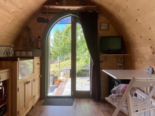 una puerta arqueada a una cocina con mesa y TV en Robins Nest glamping pod North Wales, en Mold