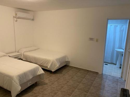 a room with two beds and a bathroom with a sink at ALOJAMIENTO ONCATIVO in Oncativo