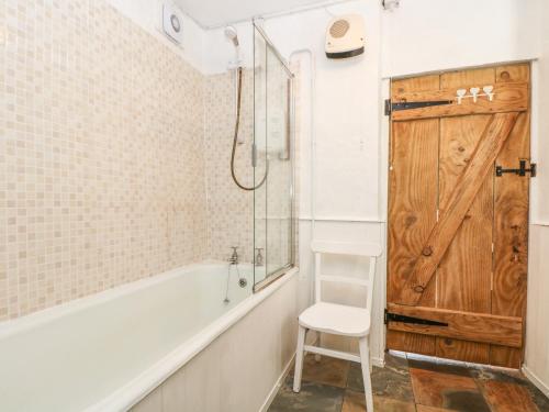 a bathroom with a white tub and a wooden door at Tinners Cottage in Saint Cleer