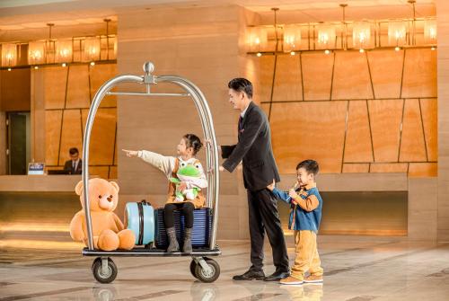 a man and two children standing next to a luggage cart at Crowne Plaza Shenzhen Longgang City Centre by IHG in Longgang