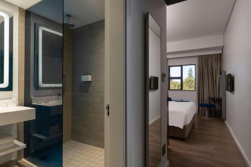 a bathroom with a shower and a sink and a bed at Park Inn by Radisson Polokwane in Polokwane