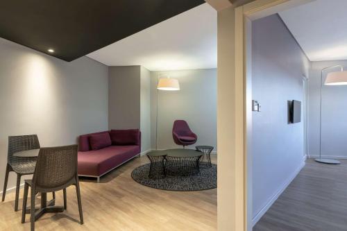 a waiting room with a red couch and tables and chairs at Park Inn by Radisson Polokwane in Polokwane