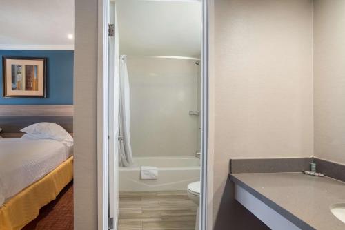a bathroom with a shower and a toilet and a bed at SureStay Hotel by Best Western San Rafael in San Rafael