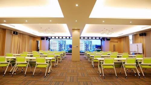 a room with rows of tables and green chairs at Holiday Inn Shanghai Dishui Lake by IHG in Nanhui