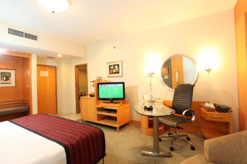 a hotel room with a bed and a desk and a television at Lakeshore Hotel & Apartments in Dhaka