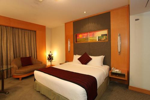 a hotel room with a large bed and a chair at Lakeshore Hotel & Apartments in Dhaka