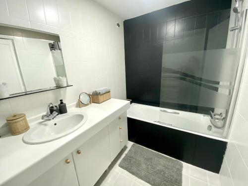La salle de bains blanche est pourvue d'un lavabo et d'un miroir. dans l'établissement Quimper: T3 avec vue cathédrale proche gare, à Quimper