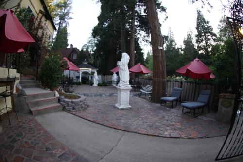 a statue in the middle of a patio with tables and chairs at FLEUR DE LAC EUROPERAN INn in Lake Arrowhead