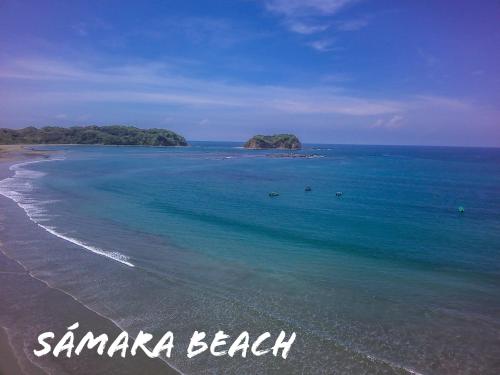 a beach with an island in the ocean at Cabañas Lamaite in Sámara