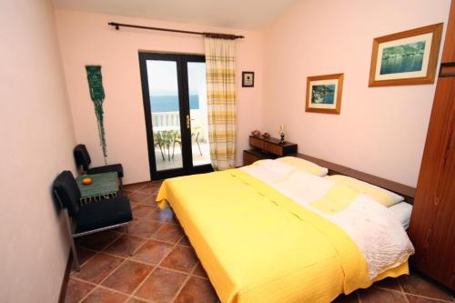 a bedroom with a yellow bed and a balcony at Apartments by the sea Pisak, Omis - 1070 in Mimice