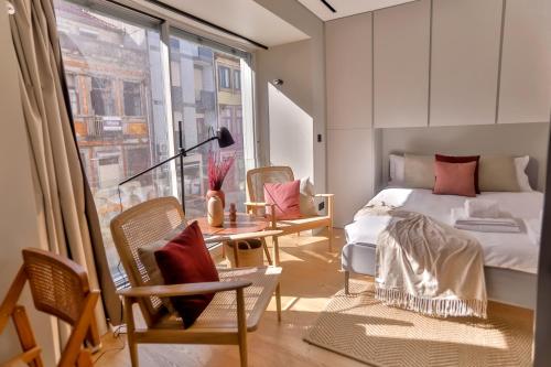 a bedroom with a bed and chairs and a window at Alegria Suítes By Porto City Hosts in Porto