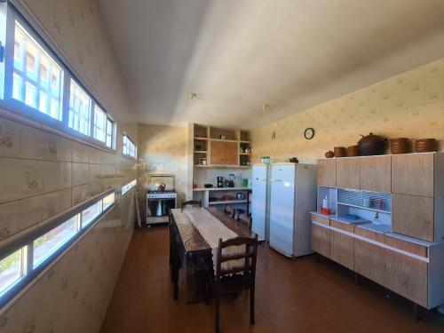 a large kitchen with a table and a refrigerator at Casa Morada das Flores in Areia