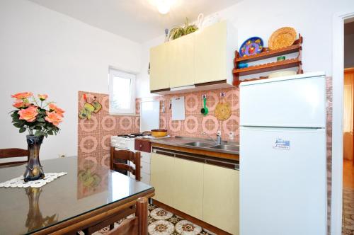 una cocina con nevera y una mesa con un jarrón de flores en Apartments by the sea Arbanija, Ciovo - 1085 en Trogir