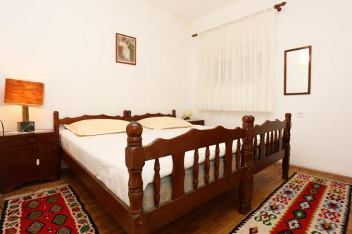 1 dormitorio con cama de madera y alfombra en Apartments by the sea Okrug Gornji, Ciovo - 1111 en Trogir