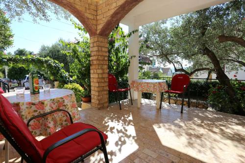 un patio al aire libre con mesas, sillas y árboles en Apartments by the sea Okrug Gornji, Ciovo - 1111 en Trogir
