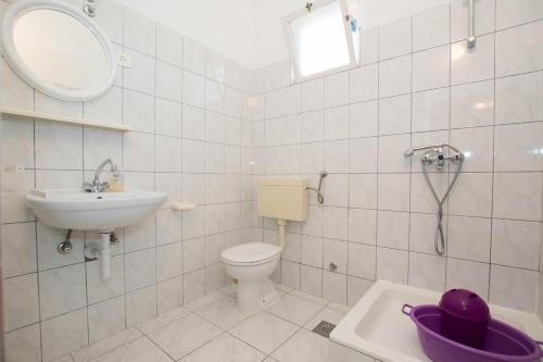 ein Badezimmer mit einem Waschbecken, einem WC und einem Spiegel in der Unterkunft Apartment Arbanija 1122a in Trogir