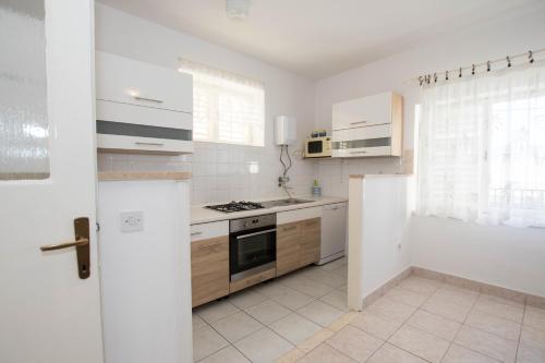 cocina con armarios blancos y fogones en Apartment Arbanija 1122a en Trogir