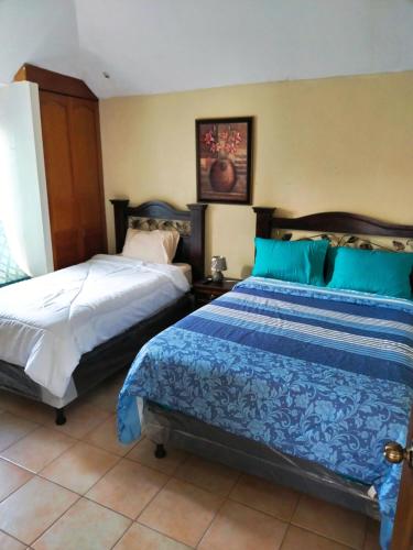 a bedroom with two beds with blue and white sheets at Sky Garden in Guatemala