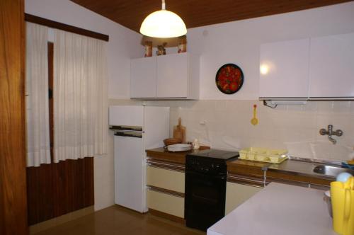 a kitchen with white cabinets and a black refrigerator at Apartments by the sea Vinisce, Trogir - 1166 in Vinišće
