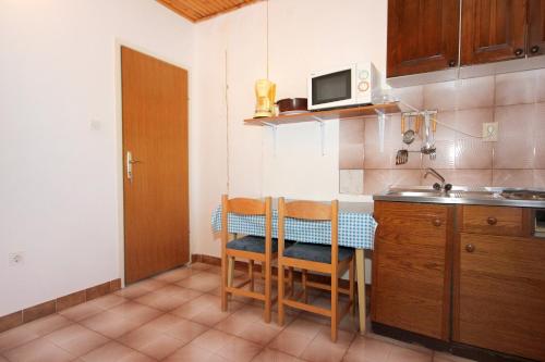 a small kitchen with a table and a microwave at Apartments and rooms by the sea Mandre, Pag - 3557 in Kolan