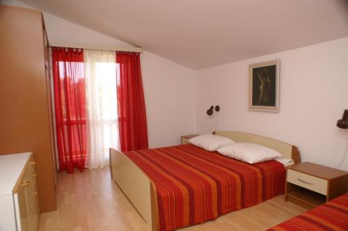 - une chambre avec un lit et une fenêtre avec des rideaux rouges dans l'établissement Family friendly apartments with a swimming pool Vodice - 4235, à Vodice